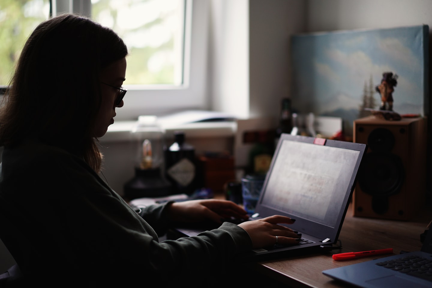 Person working on a laptop at a wooden desk.